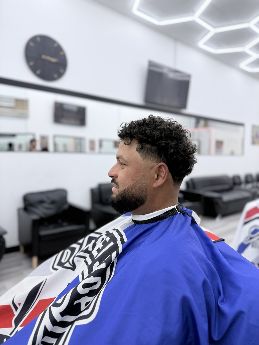 Curly haircut with a clean fade and shaped beard at Luke's Barber Shop